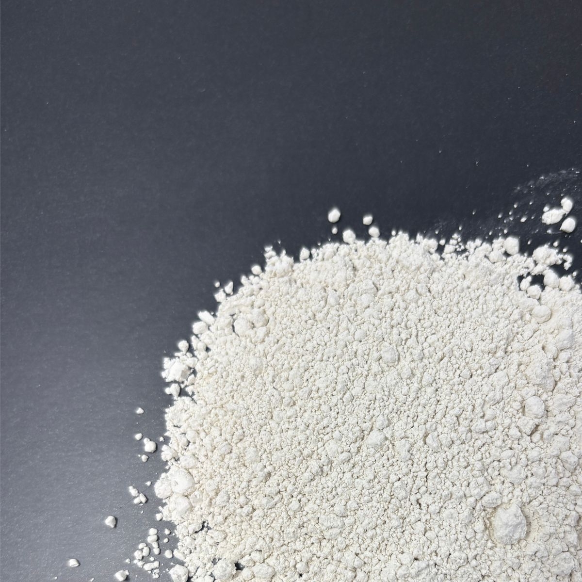 Feines weissliches Calciumsulfatpulver auf dunklem Untergrund verteilt