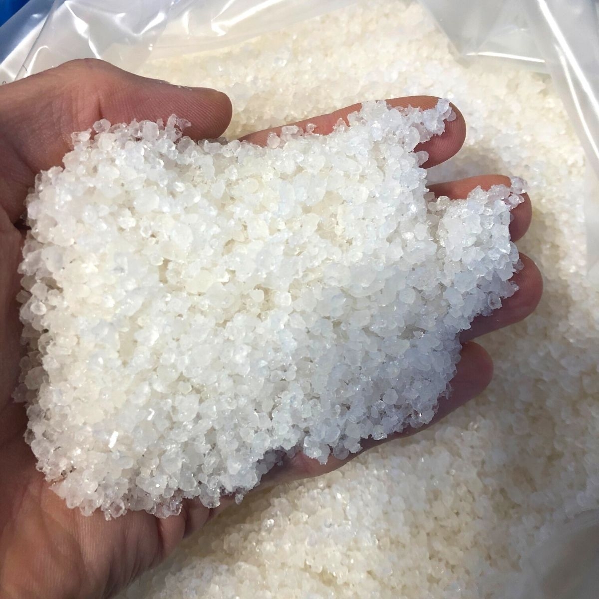 Hand haelt grobkoerniges Badesalz aus dem Toten Meer