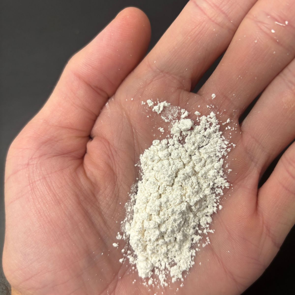 Calciumcarbonat-Pulver lose in einer Hand gezeigt