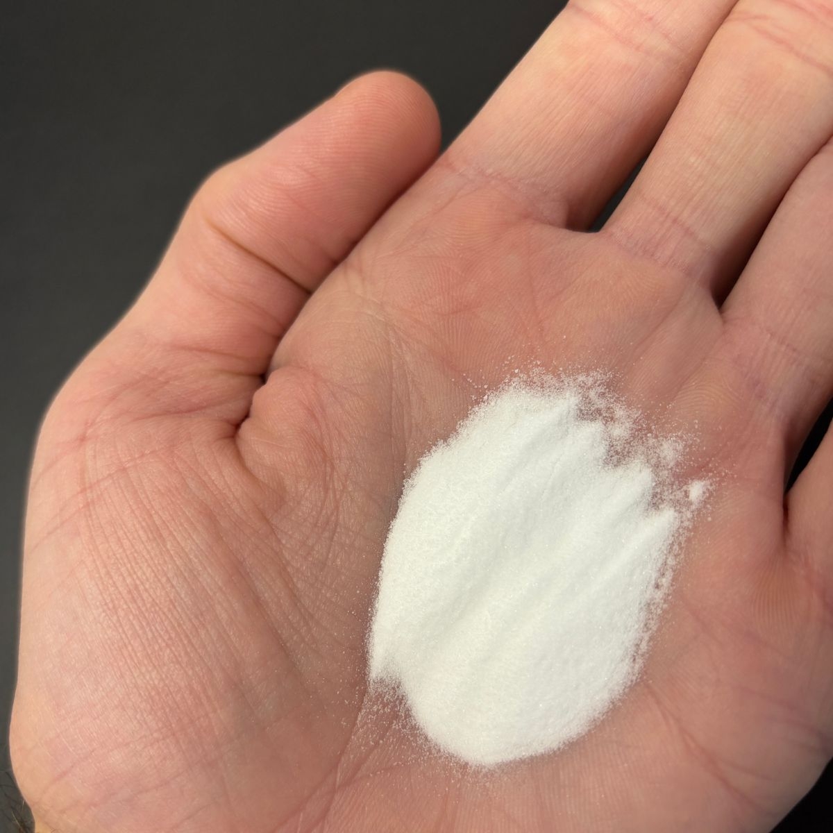 Hand haelt feines weisses Natriumsulfat-Pulver