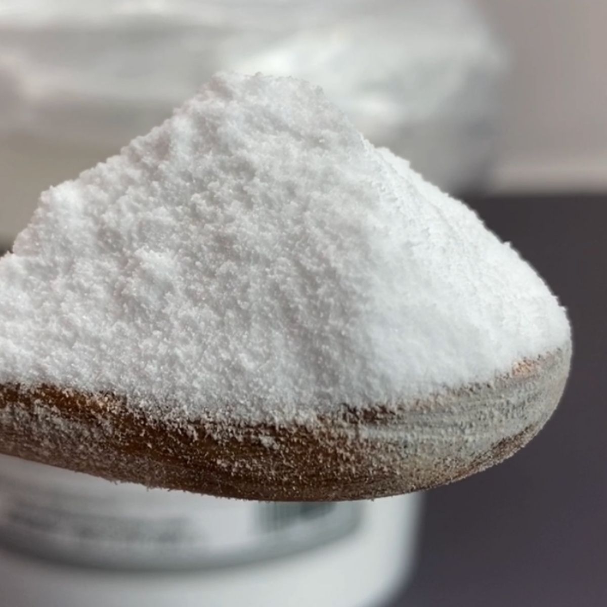 Nahaufnahme weisses Natronpulver auf Holzloeffel