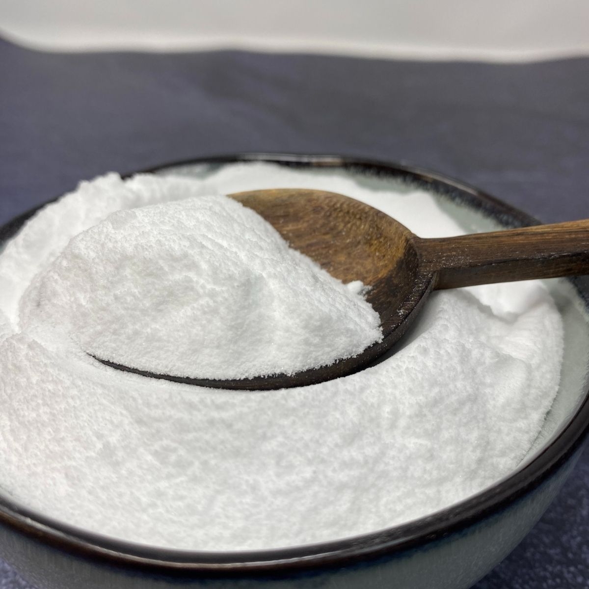 Schale mit weissem Natronpulver und Holzloeffel