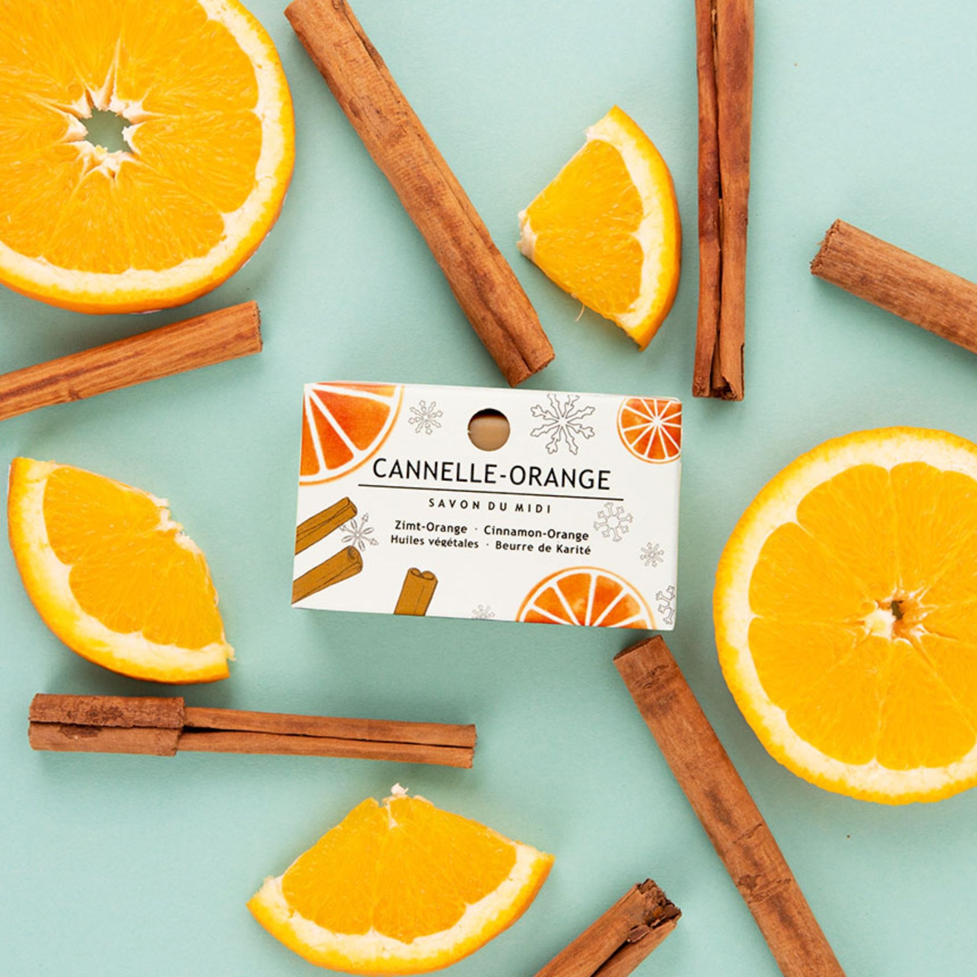 Winterseife Cannelle-Orange 100g mit Karitébutter_ dekoriert mit frischen Orangenscheiben und Zimtstangen auf hellem Hintergrund