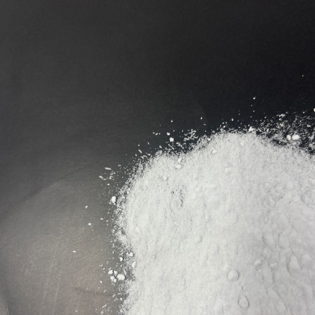 Weisse Dextrose-Pulverstruktur auf dunkler Oberflaeche verstreut