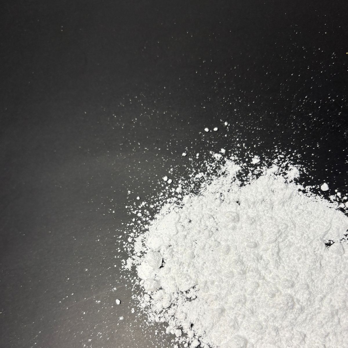 Feines weisses Calciumcitratpulver auf dunklem Untergrund verteilt