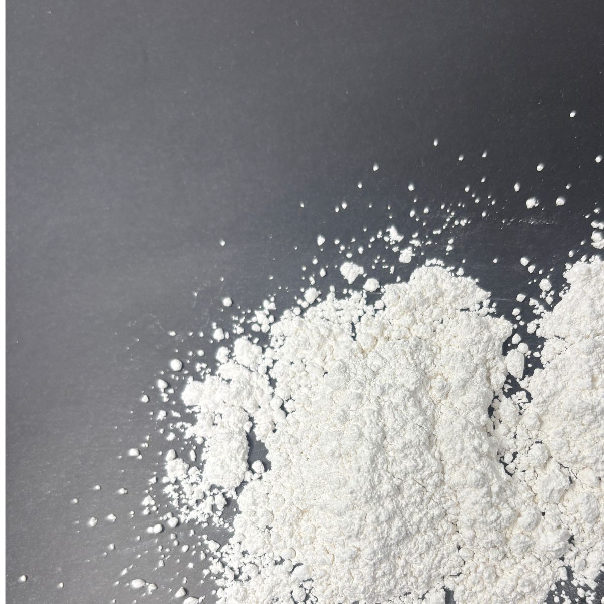 Weisses Calciumcarbonat-Pulver auf grauem Hintergrund verteilt