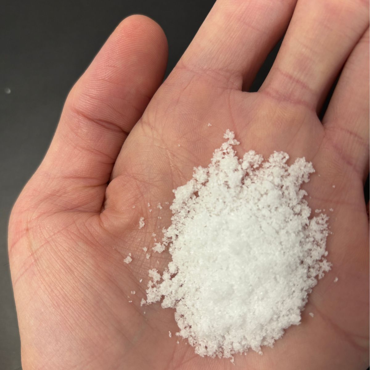 Hand haelt eine Portion weisses Magnesiumchlorid-Pulver