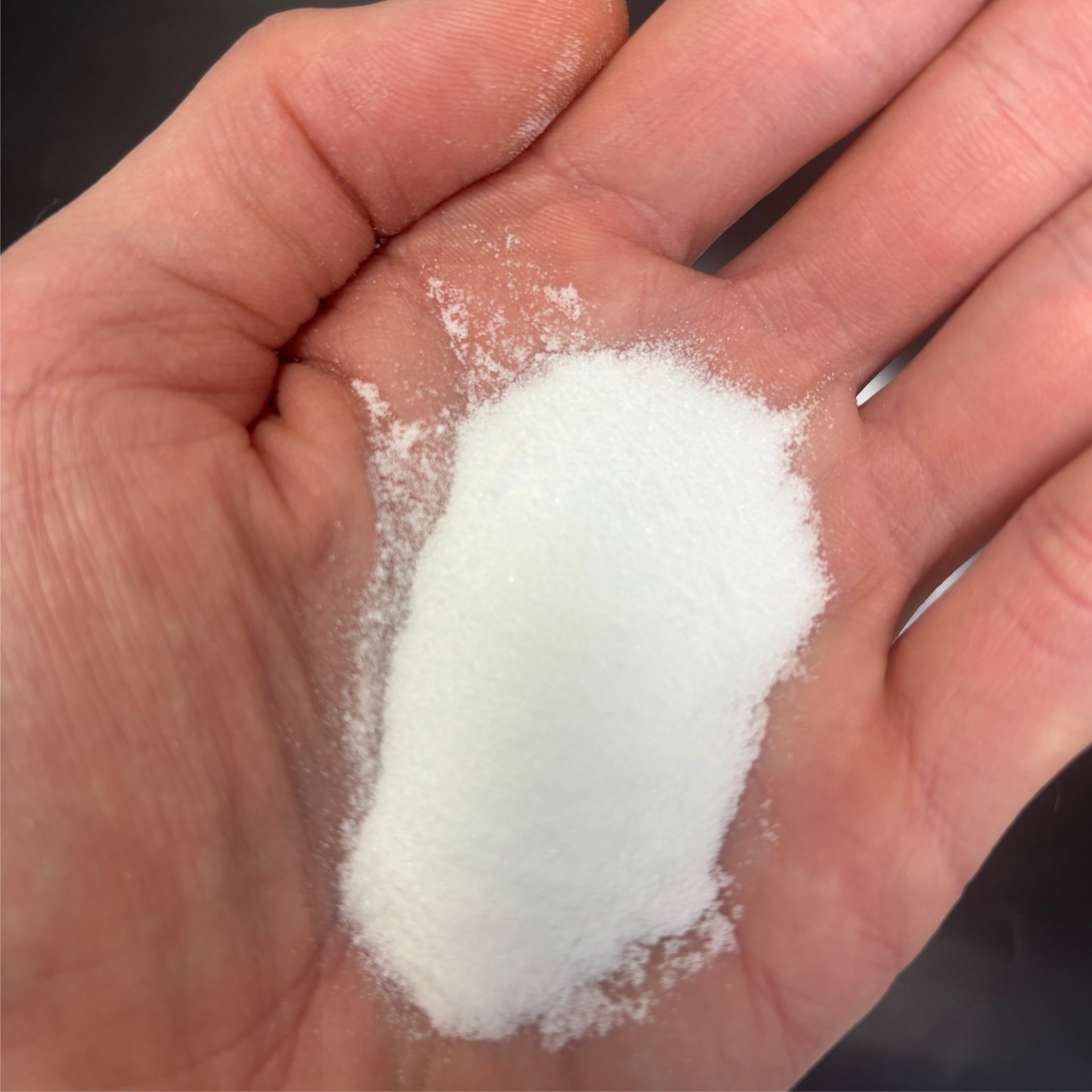 Feines weisses MSM Pulver auf einer geoeffneten Hand als Detailaufnahme