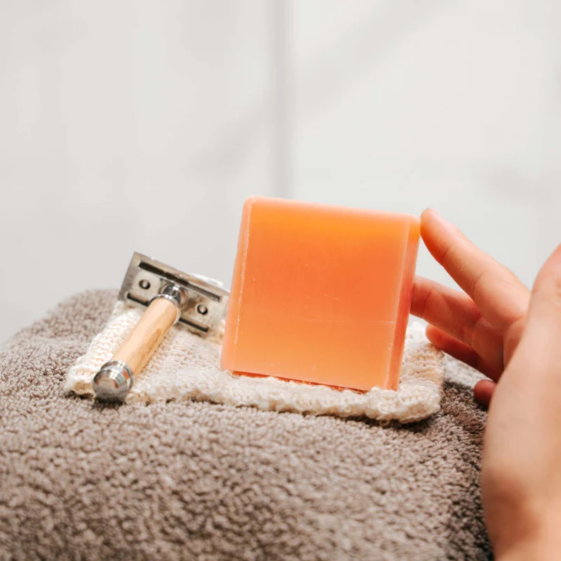 Aloe Vera _ Lime Seife liegt auf Handtuch neben Rasierer und wird mit der Hand beruehrt