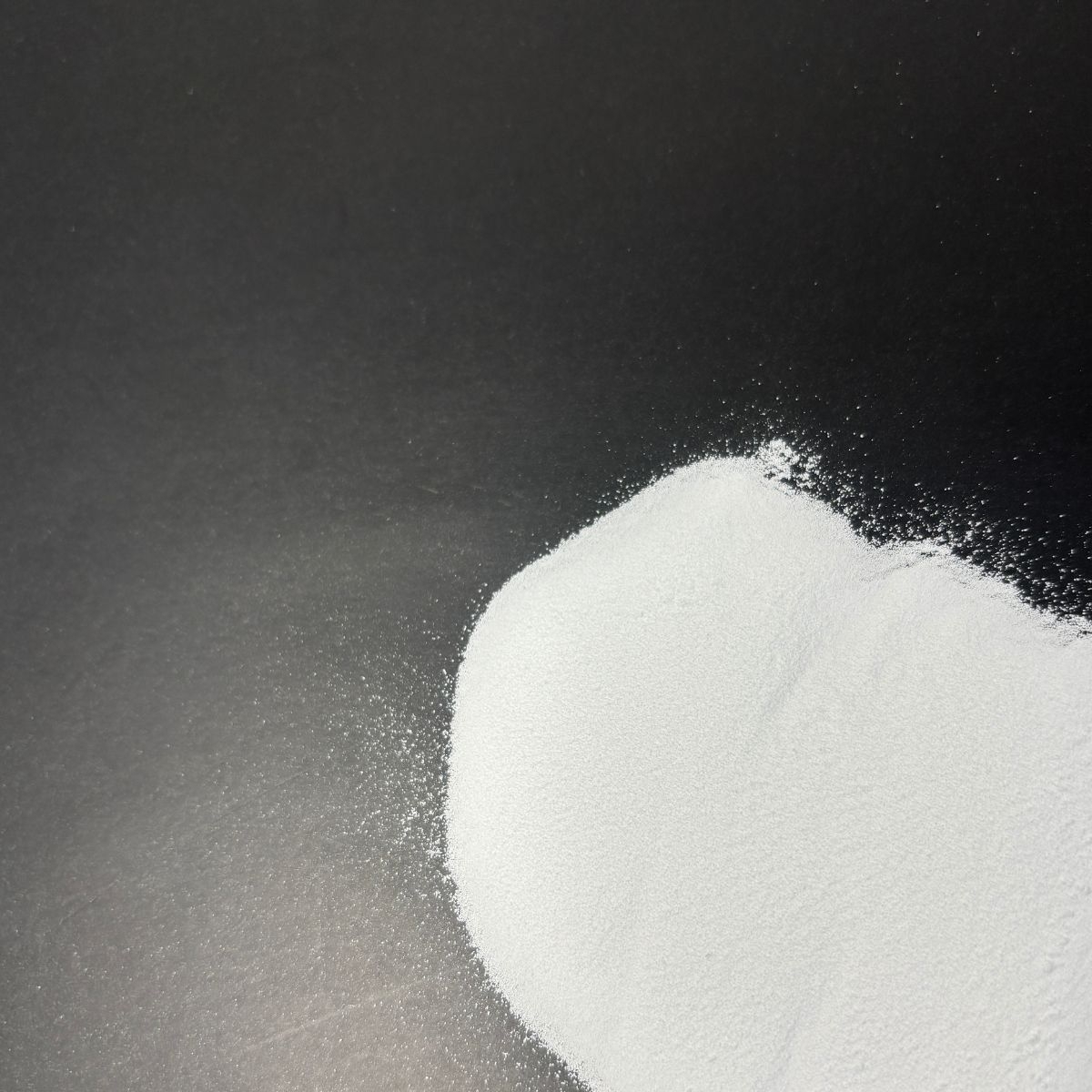 Feines weisses Magnesiumcitratpulver auf dunklem Untergrund verteilt