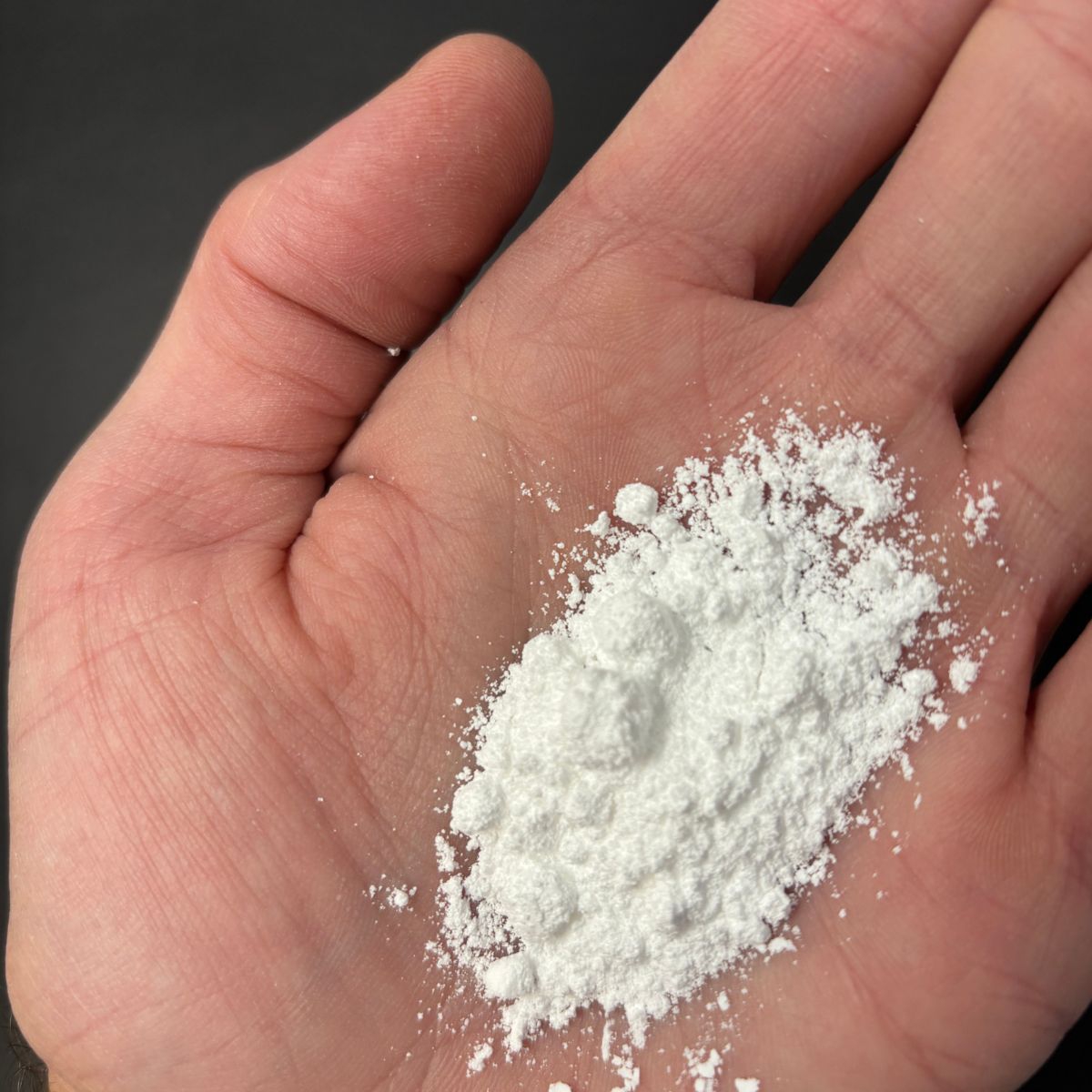 Weisses Calciumcitratpulver lose in einer geoeffneten Hand