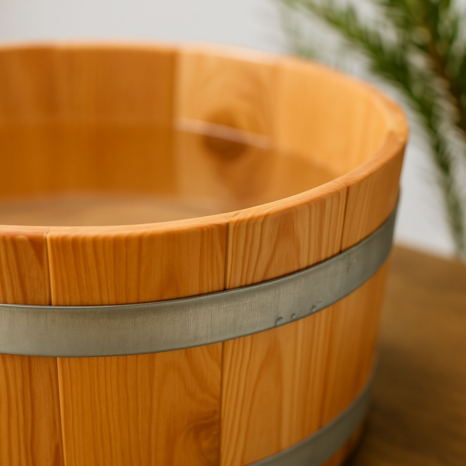Detailaufnahme einer Fussbadewanne aus Laerchenholz mit Metallreifen_ gefuellt mit Wasser_ auf einem Holztisch platziert