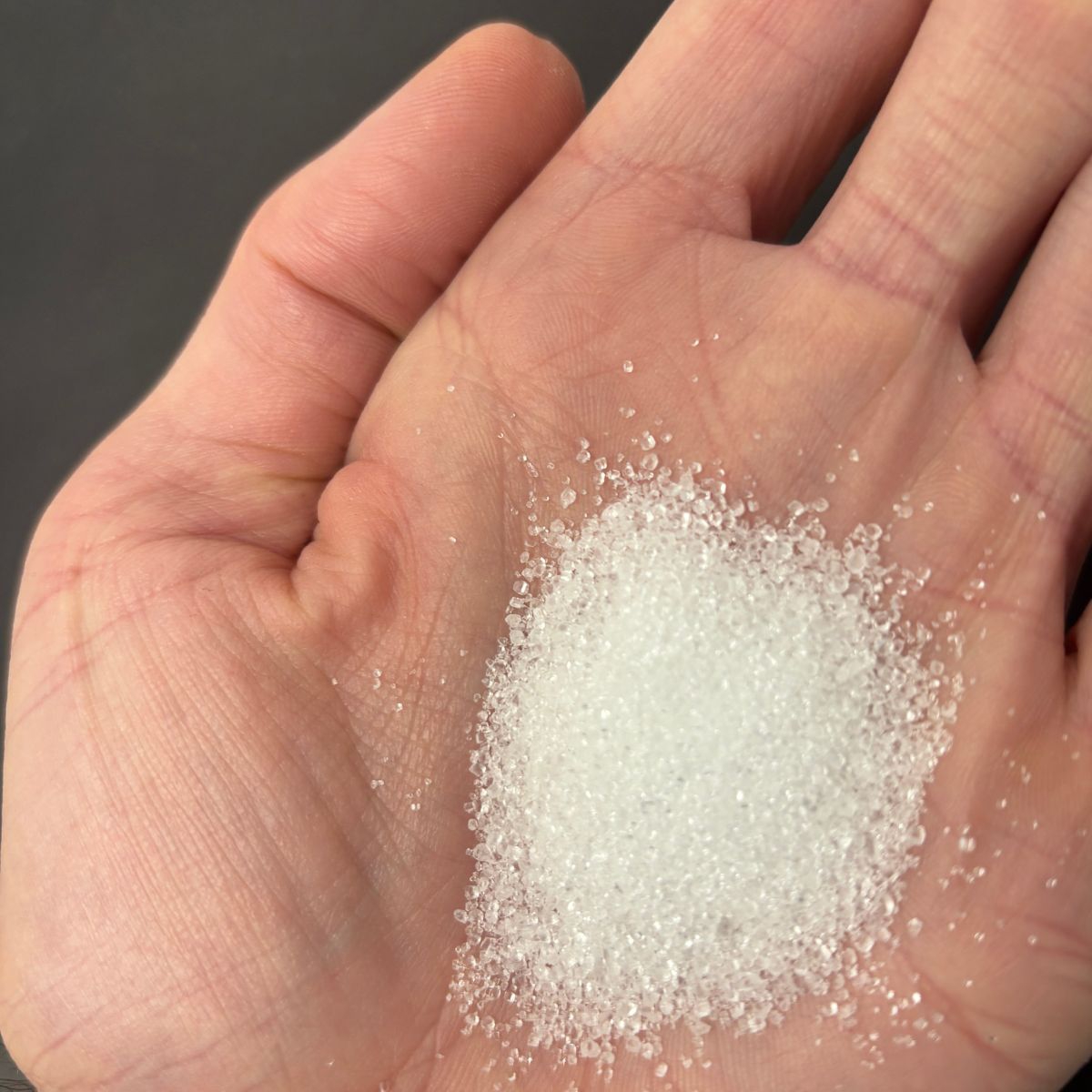 Zitronensaeure-Kristalle auf einer Handflaeche verteilt