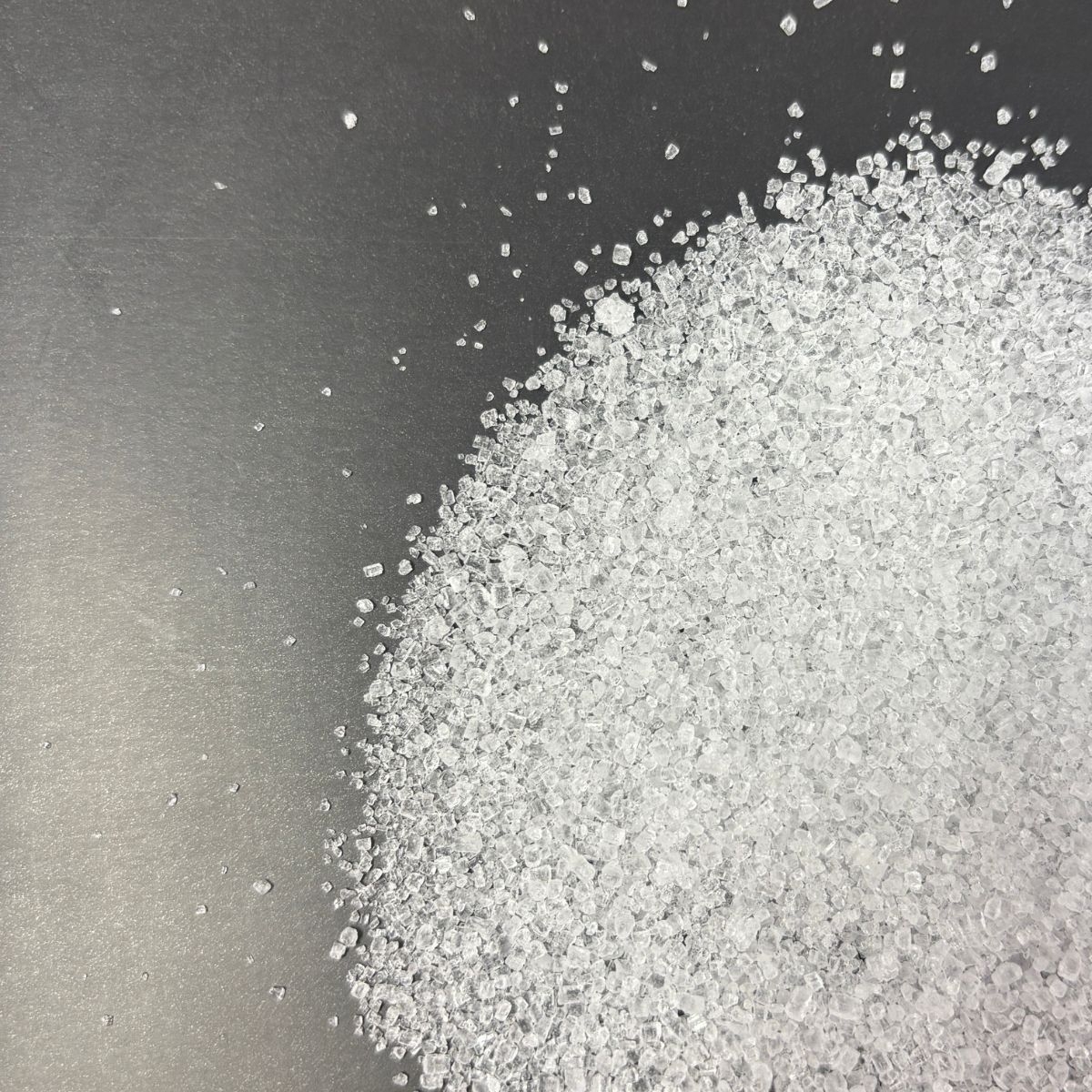 Naheaufnahme klarer Kristalle von Natriumthiosulfat auf dunklem Hintergrund