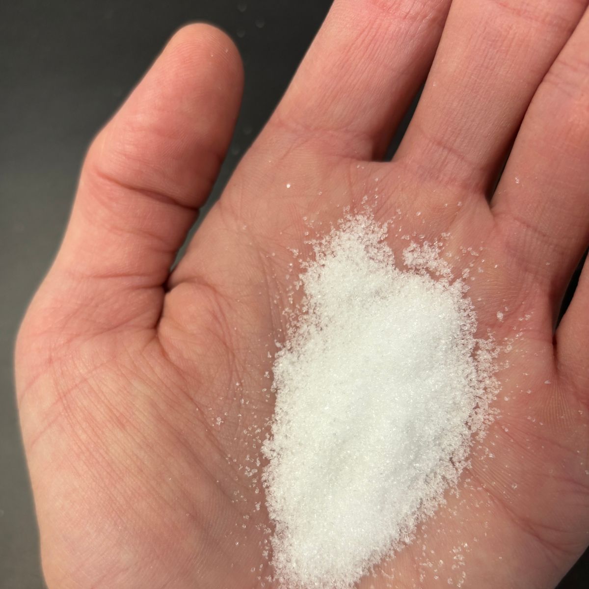 Weisses Kaliumcitrat lose in einer geoeffneten Hand